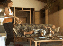 a man laying on a couch next to a table with a bottle of corona on it