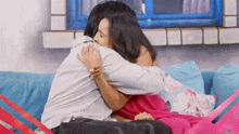 a man and a woman are hugging each other on a blue couch .