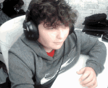 a man with curly hair wearing headphones and a nike sweatshirt