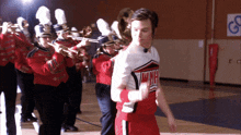 a cheerleader in a wmhs uniform is dancing in front of a marching band