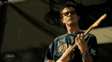 a man playing a guitar with a shirt that says ' rat ' on the sleeve