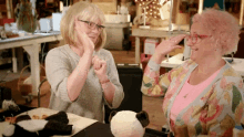 two women are sitting at a table with a stuffed animal on it .