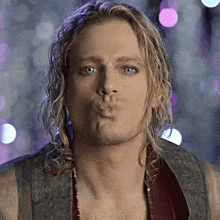 a man with long blonde hair is making a kissing face