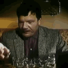 a man is sitting at a table with a bunch of glasses of wine .