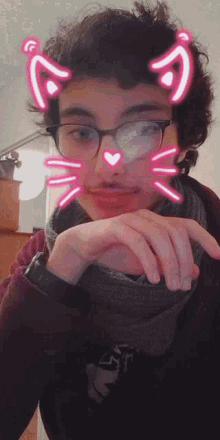 a young man wearing glasses and a scarf has a cat face sticker on his face