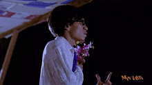 a man holding a bouquet of flowers in front of a sign that says man laksa