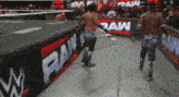 two wrestlers are walking across a wrestling ring with a sign that says raw