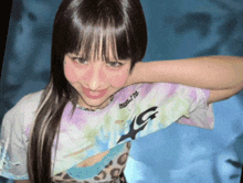 a woman wearing a tie dye shirt with the letter g on the sleeve