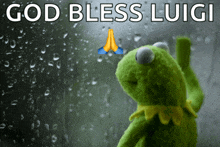 a kermit frog praying in front of a window with the words god bless luigi above it
