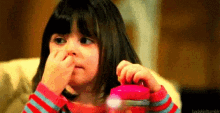 a little girl is sitting on a couch eating a candy cane .