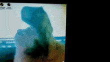 a blurred image of a person standing on a beach with a few icons on the bottom of the screen