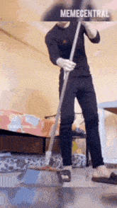 a man is cleaning the floor with a broom in a bedroom .