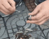 a person is holding a broken car key in their hands while sitting on a tiled floor .