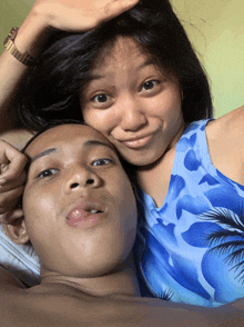 a man and a woman are posing for a picture and the woman is wearing a blue floral top