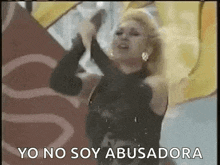 a woman in a black dress is dancing with her arms in the air and the words `` yo no soy abusadora '' .