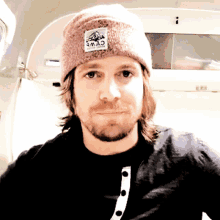 a man wearing a pink beanie with a patch that says a.m.a.c.