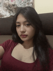 a woman in a red shirt is sitting on a couch and taking a selfie