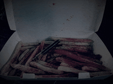 a box filled with french fries with a tong in it