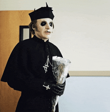 a man dressed as a priest holding a bouquet of flowers