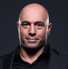 a bald man with a beard is wearing a black jacket