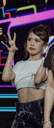 a woman in a white crop top with the word tee on it