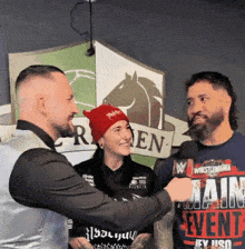 a man wearing a wrestlemania shirt is talking to two other people
