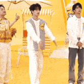 three young men are standing in front of a yellow sign that says ' coca cola ' on it
