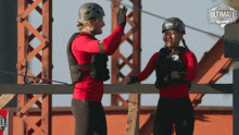 two people giving each other a high five in front of a sign that says the ultimate