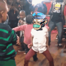 a group of children are dancing in a room with a tribe logo on the bottom