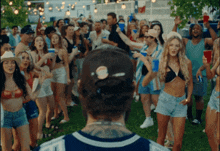 a man in a baseball cap stands in front of a crowd of people at a party