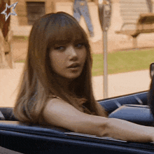 a woman with long hair is sitting in a car with a star in the background
