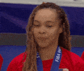 a woman wearing a red shirt and a blue fiba world medal around her neck