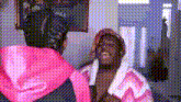 a woman in a pink hoodie is standing next to a man in a pink robe in front of a mirror .