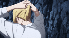 a person is holding their hair in a ponytail in front of a rock wall
