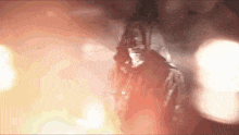 a man in a hoodie is standing in front of a fire .