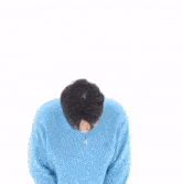 a young man wearing a blue sweater is making a heart shape with his hands .