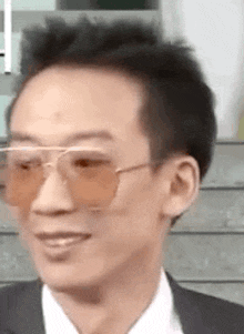 a close up of a man wearing sunglasses and a suit smiling .