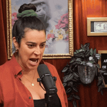 a woman screams into a shure microphone in front of a painting of a gorilla