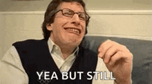a man wearing glasses and a vest is making a funny face and saying yea but still .