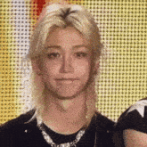 a close up of a person with long blonde hair wearing a black shirt and necklace .