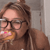 a woman wearing glasses is eating a hamburger with a hello kitty on it