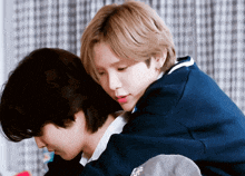 two young men are hugging each other with one wearing a blue sweater