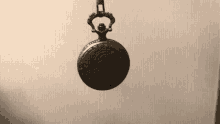 a pocket watch is hanging from a chain on a wall