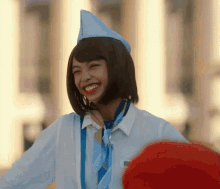 a woman wearing a blue hat and tie smiles for the camera