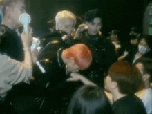 a man with red hair is kissing another man in a crowd of people .