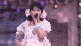 a girl singing into a microphone with a flower in her hair