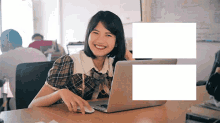 a woman is sitting at a desk with a laptop and a mouse