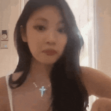 a close up of a woman wearing a cross necklace .