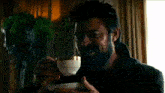 a man with a beard is drinking from a cup of tea .