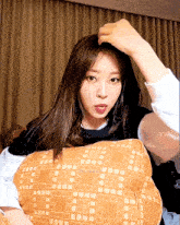 a woman is sitting on a bed with a pillow that has a pattern of squares
